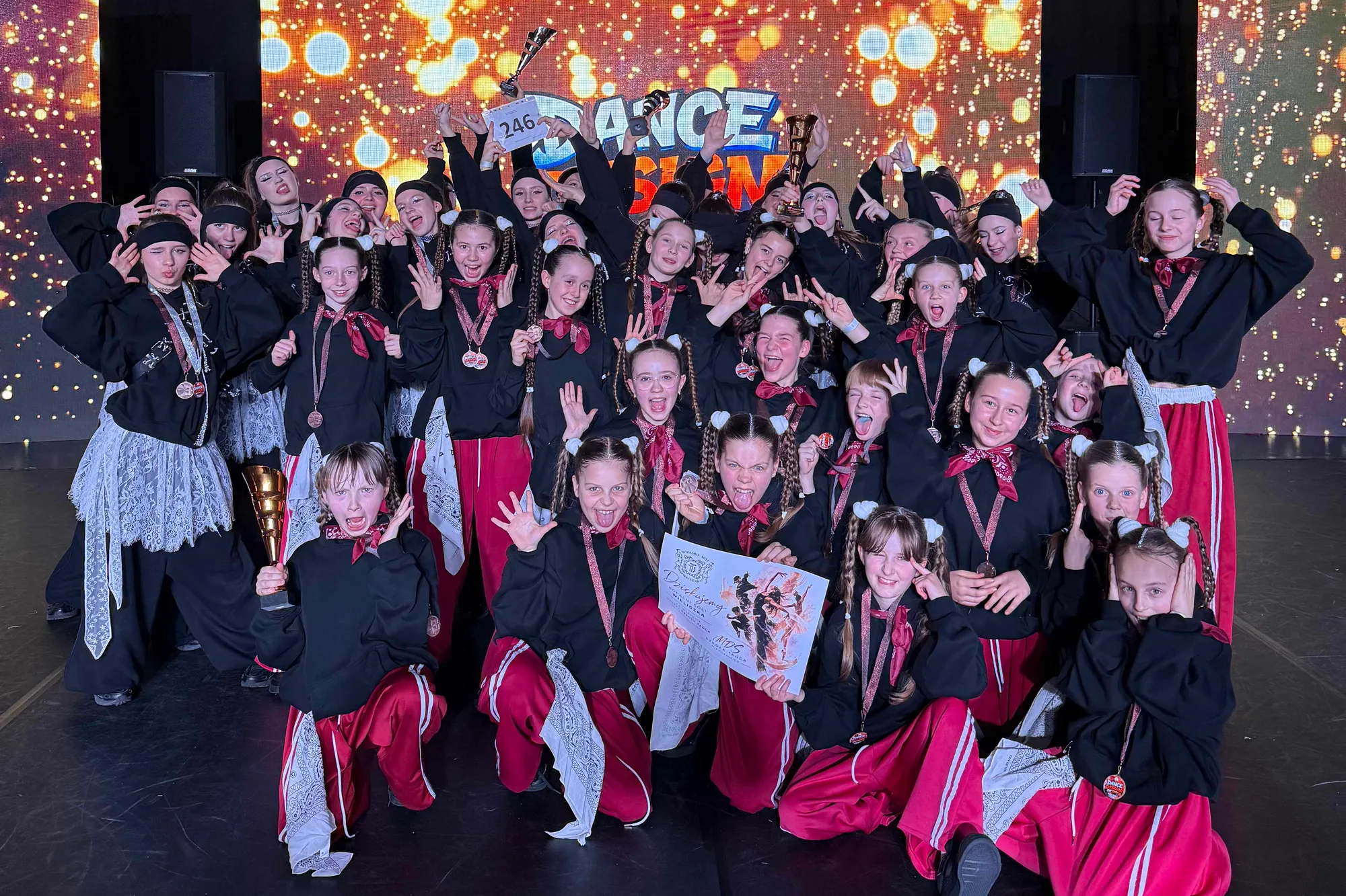 Tancerki MDS w czerwono-czarnych strojach cieszą się z medali i pucharów na scenie Dance Design
